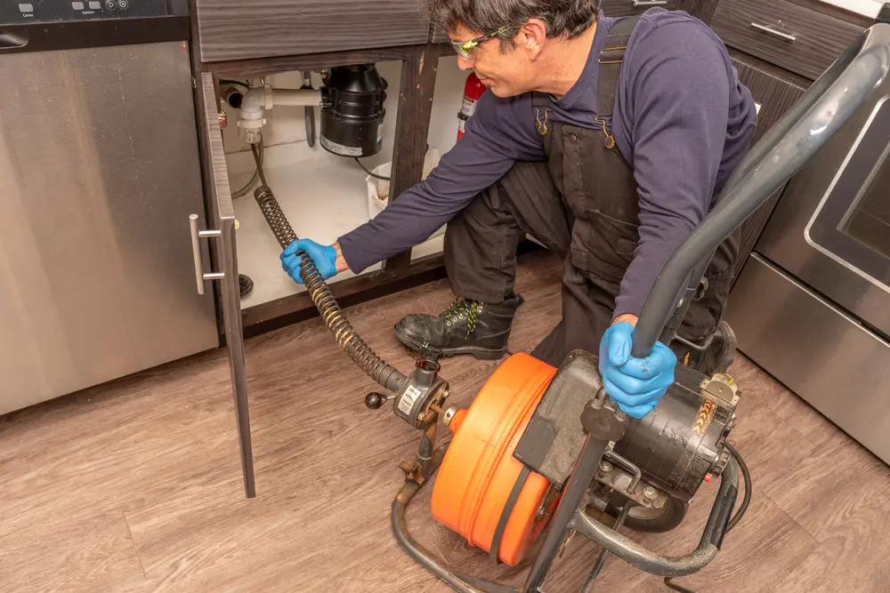 plumber using an auger to unclog a clogged drain
