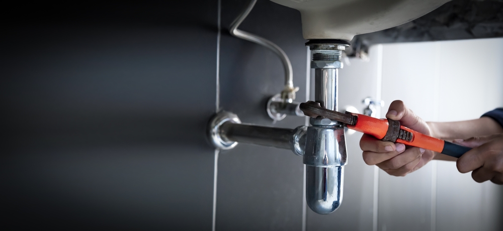 Plumber uses wrench to repair water pipe under sink There is maintenance to fix the water leak in the bathroom.