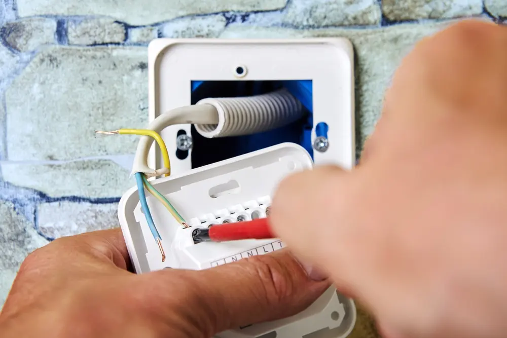 Wiring new electrical socket of thermostat in stone wall, Electrician Installing, connecting live neutral and ground wires, work involved in electrical fittings.